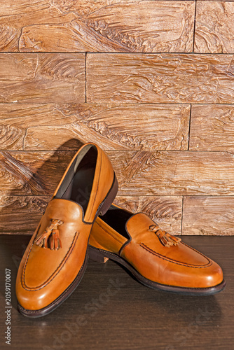 Tan Tassel Loafers Shoes Made of Calf Leather with Leather Sole Placed On Wooden Surface Against Grunge