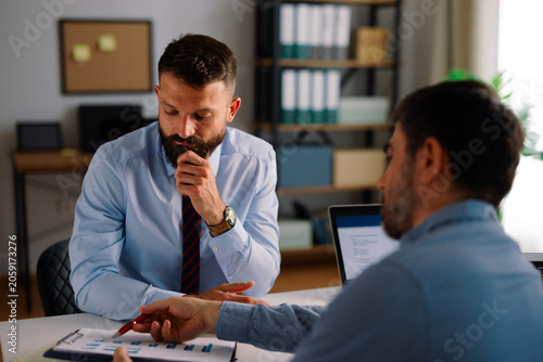 Photos Businessmen analyzing financial report data during meeting