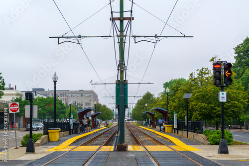 Symmetrical view of Boston light rail station with tracks, overhead wires, and center catenary pole
