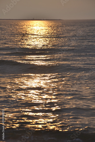 Sunset reflection on calm ocean waves with golden light  