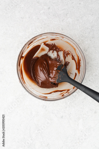 Overhead view of melted dark chocolate on a glass bowl on a white countertop, top view of melted chocolate for baking