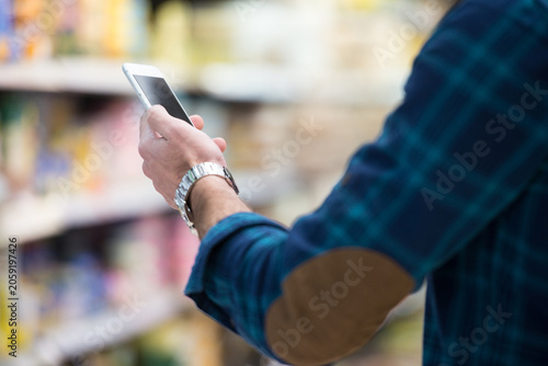 Obraz na płótnie Man Using Mobile Phone While Shopping In Supermarket