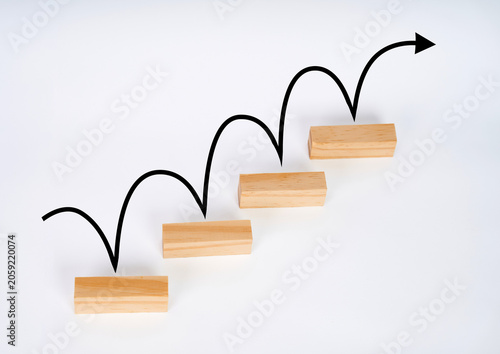 Fotografie Wooden blocks with a bouncing upward arrow, representing step by step growth, business progress and strategic advancement