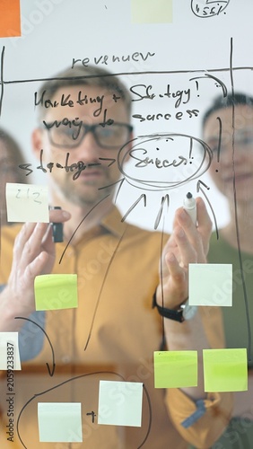 Fotografie Business people colleagues brainstorming, writing strategy notes on glass board,