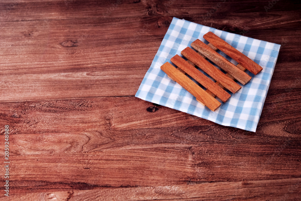 Fototapeta premium Wooden rest neatly on a checkered cloth. The cloth blue and white pattern adds a gentle contrast. Soft lighting highlights their natural wood grain. Crafted for minimalist, eco-friendly aesthetics