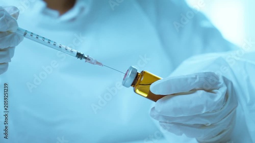 Scientist Drawing Liquid Sample from Pharmaceutical Vial Using Syringe.  Drug development, laboratory procedure, pharmaceutical testing, healthcare innovation