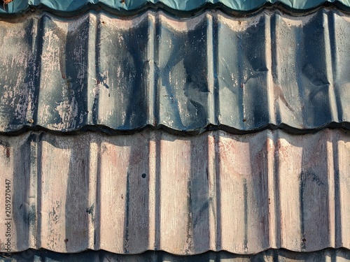 Weathered corrugated roof tiles texture showing aged dark and dusty brown ceramic tiles close up for abstract architectural background design