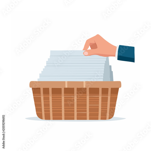 Hand holding stack of papers over wicker basket