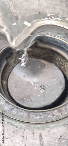 Close up of a drain  in a sink as water goes down while spinning.