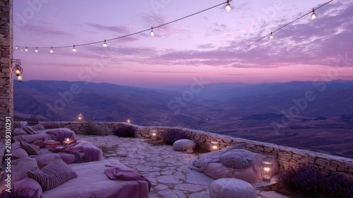 Outdoor stone terrace lounge area overlooks a vast mountain landscape at twilight
