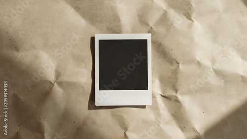 Blank polaroid photograph on crumpled kraft paper texture