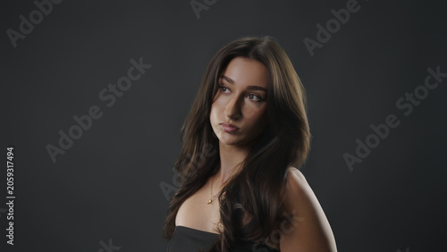Young woman contemplating, with a serious expression, looking up in a studio