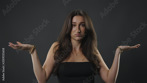 Foto Young woman shrugging with open palms, expressing confusion, doubt, and choice