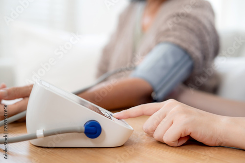 Asian woman nurse measuring blood pressure senior patient, medical checking for hypertension monitoring, caregiver support elderly woman with arterial blood pressure device, routine health checkup.