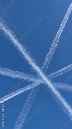 Dynamic airplane contrails forming a starburst pattern against a clear blue sky, cinematic slow-motion aerial perspective, symbolizing travel, freedom, adventure