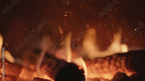 Small orange ember particles float through dark smoky atmosphere with warm cinematic fire glow