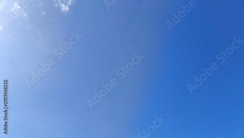 Clear blue sky with sunlight and soft thin white cloud backgrounds. Copy space. Summer blue sky. Sky only background. Natural nature design element.