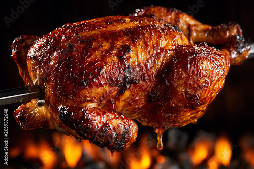 whole chicken turning on a traditional rotisserie over hot coals