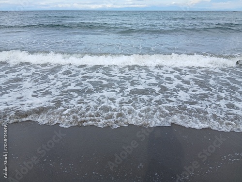 砂浜に打ち寄せる白い波と海の背景素材