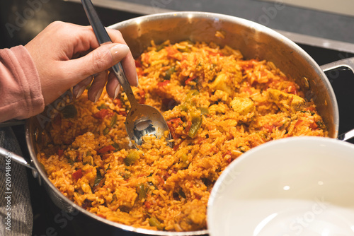 Photography hands serving a homemade rice dish from a cooking pot, representing creative use of leftovers and budget-friendly meal preparation