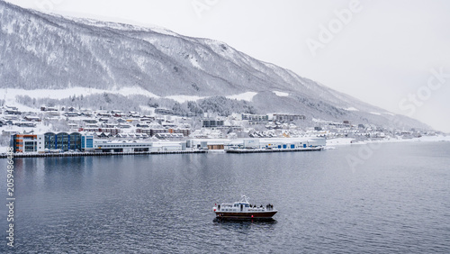 Photos Small boat on a winter fjord beside snow covered Tromso in Norway