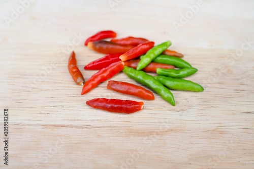 Fotografie Several fresh bird's eye chilies lie on a wooden cutting board