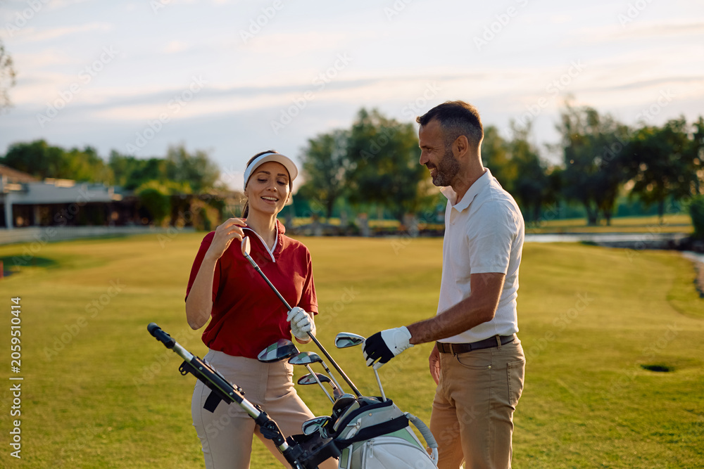 Naklejka premium Happy couple choosing a golf club on golf course.