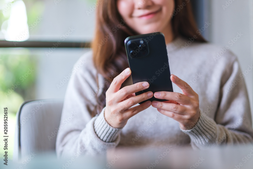 Fototapeta premium Closeup image of a woman holding and using mobile phone