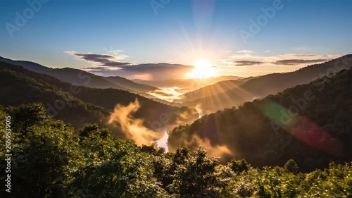 Sun rising over misty mountains and lush green valleys