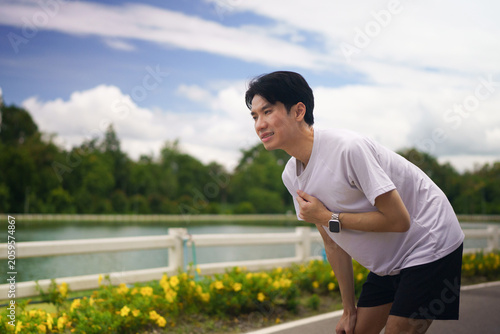 Foto Asian Man Experiencing Chest Pain While Running Outdoors in Park