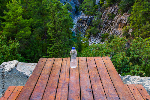 Bottle of water on wooden table. Deep canyon on a background