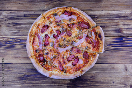 Pizza with salami sausage and parmesan cheese on a wooden table. Top view