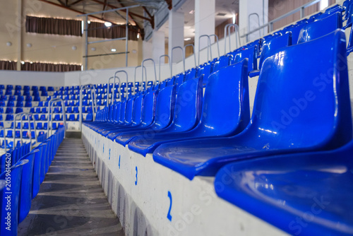 Canvastavla Rows of empty blue plastic seats in an indoor sports arena stadium