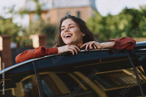 Foto A young woman leans from a car window, laughing with carefree joy during a casua