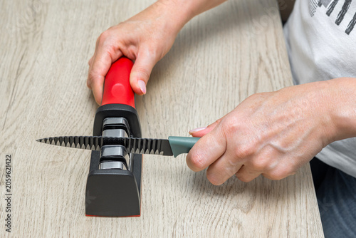Billede på lærred A housewife sharpens a kitchen knife