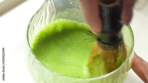 4K Traditional matcha tea preparation with bamboo whisk in ceramic bowl, Close-up of vibrant green tea being mixed Japanese culture healthy lifestyle mindfulness and wellness.
