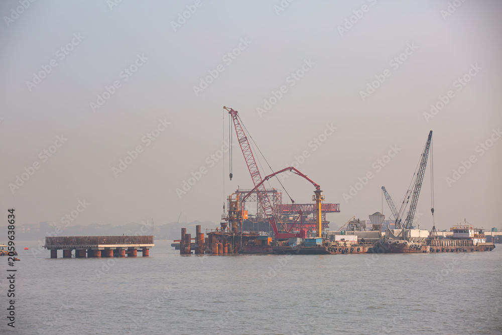 Fototapeta premium Piling cranes on barge hammering a concrete piles into sea - Offshore oil and gas sea construction at port of Mumbai, india