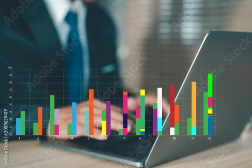 Business professional analyzing financial data and growth statistics on a laptop with colorful bar chart overlay. Concept of  investment, reporting, strategy, and digital business intelligence.