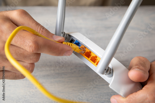 Φωτογραφία Man plugging internet cable into wifi router.