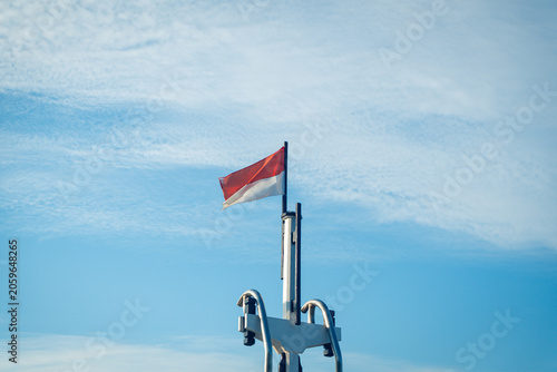 indonesian national flag waving against blue sky with clear clouds