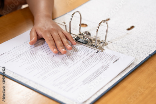 Fotografie Close-up of a hand arranging paperwork inside a ring binder folder