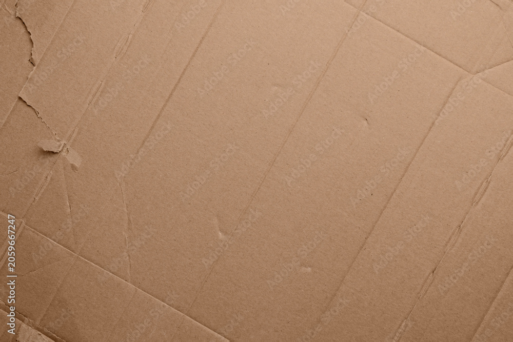 Fototapeta premium Brown kraft cardboard surface with fold marks, soft creases and authentic paper texture. Minimal abstract background from recycled packaging material