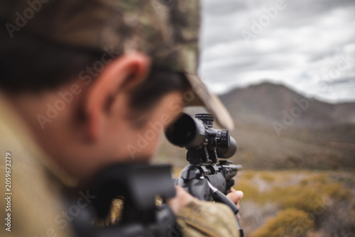 Slika na platnu Hunter aiming rifle with telescopic sight in mountain landscape