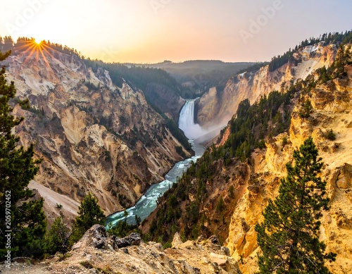 Majestic view of a cascading waterfall flowing through a deep canyon at sunrise