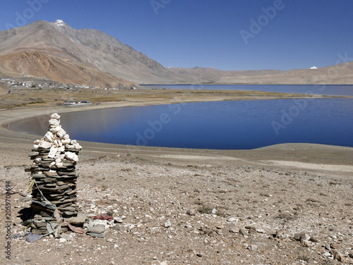 Cairn made of stones in front of tso moriri lake and himalayan mountains in Ladakh, near Korzok. Scenic landscape in summer