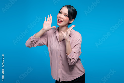 Cheerful young Indonesian woman shouting with hands near mouth