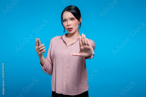 Serious Asian Woman Holding Smartphone and Making Stop Hand Gesture