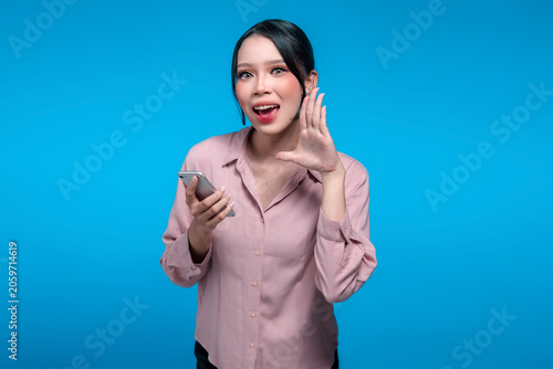 Excited Asian Woman Holding Smartphone and Whispering a Secret