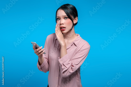 Foto Surprised Asian Woman Holding Smartphone and Whispering a Secret