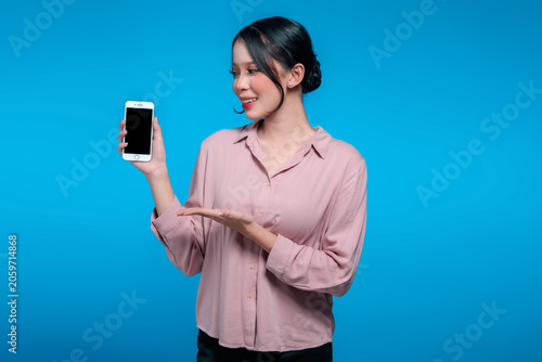 Smiling Asian Woman Looking at and Presenting Blank Smartphone Screen